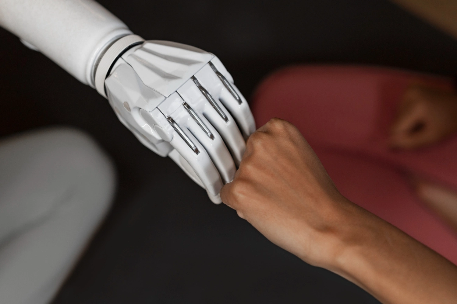 A robot hand and a woman's hand in a fist bump, symbolizing the collaboration between human creativity and AI as a business tool.