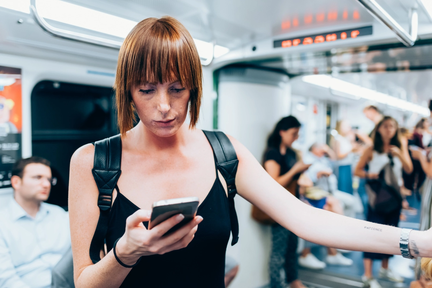 A woman on a subway looking at her mobile phone, representing the moment a Strategic Narrative reaches a niche audience through social ad funnels.